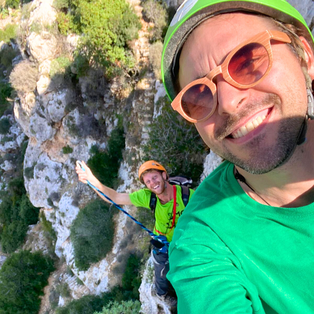 Client taking a smiling selfie on the Via Ferrata in Malta with an MC Adventure guide smiling in the background.