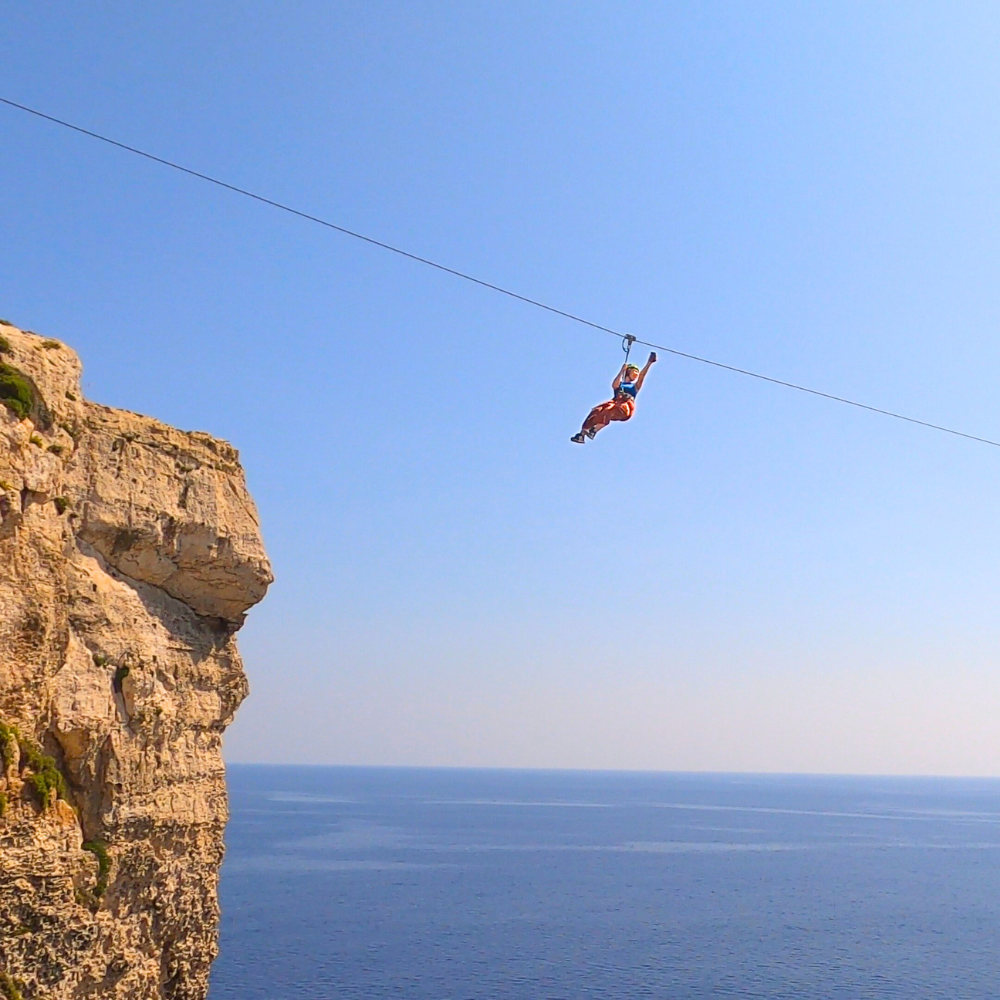 Girl taking a selfie while riding the zipline, secured with harness and trolley.