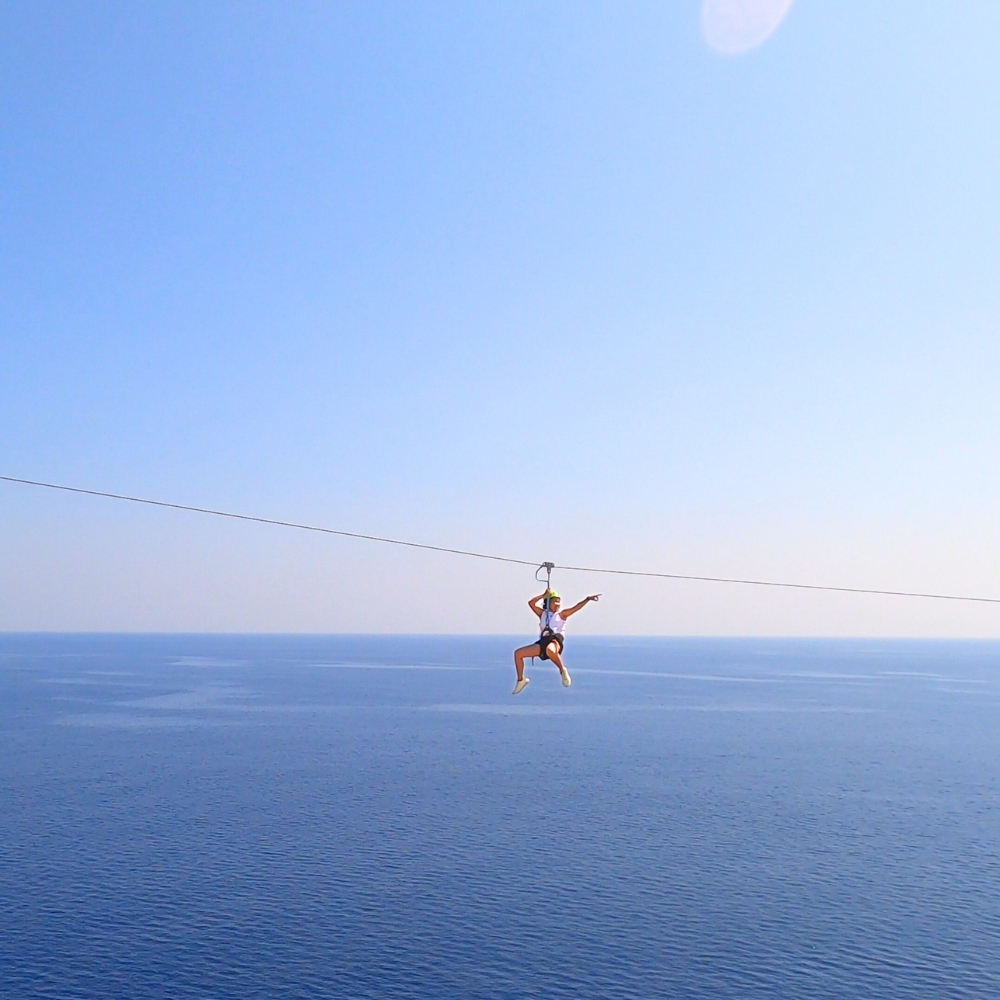 Woman riding the zipline in Malta, secured with harness and trolley.
