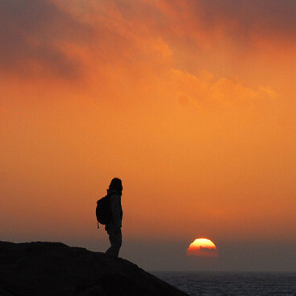 Person trekking at sunset in Malta with orange colours in the sky.